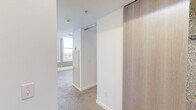 Located in the heart of downtown Des Moines at 218 6th Ave, this one-bedroom, one-bathroom unit offers a well-organized layout across a single floor. The living room is bright and open, featuring soft carpeted flooring, clean white walls, and elevated ceilings with visible HVAC vents that contribute to an airy feel. Large, multi-pane windows with roller shades frame urban views of the surrounding cityscape, filling the space with natural light.

The bedroom continues the carpeted flooring and taupe-toned wall accents, with multiple windows overlooking neighboring buildings. A modern sliding barn door in warm wood tone adds a stylish, space-saving design element, while a built-in closet area provides practical storage.

The galley-style kitchen is efficiently designed, featuring warm wood cabinetry, dark countertops, and stainless steel appliances including a range, microwave, and refrigerator. A row of tall windows along one wall brings in ample natural light and enhances the sense of space.

The bathroom is clean and bright, with white walls, a white vanity, yellow wood-toned flooring, and chrome fixtures that give it a fresh, contemporary look. A connecting hallway ties all rooms together cohesively, making this a functional and thoughtfully designed urban residence.