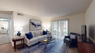 This single-story, 2-bedroom, 2-bathroom residence in Hernando, Mississippi is thoughtfully designed to maximize comfort and functionality. The living room serves as the heart of the home, featuring a textured ceiling, plush carpeting, and a large sliding glass door fitted with vertical blinds that floods the space with natural light and opens to an outdoor patio area with greenery views. The galley-style kitchen is well-appointed with light wood cabinetry, stone-look countertops, a stainless steel sink, and a full suite of appliances including an electric range, dishwasher, and refrigerator, all set atop warm hardwood-style flooring. Adjacent to the kitchen, the dining area features the same hardwood-style flooring, a ceiling fan, and pendant lighting, creating an inviting space for meals. Both bedrooms are carpeted and offer a calm, comfortable atmosphere with ample natural light from well-positioned windows. The two bathrooms are finished with tile flooring, wood-toned cabinetry with stone-look countertops, and shower/tub combinations. A tiled entryway leads into the main living space, and interior doors provide access to additional storage. The consistent neutral color palette throughout lends the home a cohesive, welcoming ambiance.