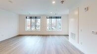 Located at 801 Orange Street in the heart of Wilmington, Delaware, this modern one-bedroom, one-bathroom unit offers a thoughtfully designed open-concept layout with contemporary finishes throughout. Light-toned hardwood-style flooring flows seamlessly across the entire space, contributing to a clean and cohesive aesthetic.

The combined kitchen and living area serves as the central hub of the unit. The kitchen is outfitted with sleek gray cabinetry, stainless steel appliances including a refrigerator, microwave, and range, and a peninsula with a white countertop and undermount sink — ideal for both meal preparation and casual dining. Recessed lighting and a modern pendant light fixture illuminate the space, while large windows frame views of the surrounding Wilmington cityscape, flooding the living area with natural light.

The bedroom is a well-proportioned, private retreat featuring large windows that offer additional urban views, including a notable church steeple on the horizon. The room benefits from generous natural light and connects to a dedicated closet for storage.

The bathroom is finished with elegant marble-style tile surrounding the soaking tub and shower, complemented by gray floor tile, a wood-toned vanity with a white countertop, and a modern rounded mirror — creating a refined, spa-inspired atmosphere.