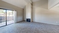 This two-bedroom, two-bathroom single-story home in Stockton, California offers a well-organized layout designed for comfortable everyday living. The living room is a standout space, featuring dramatic vaulted ceilings with exposed beam detailing, a cozy fireplace as a central focal point, and plush carpeting underfoot. Natural light filters in through a sliding glass door that opens to an outdoor area, adding an airy quality to the room. The kitchen is equipped with white cabinetry extending to the ceiling, a white electric range, and a full-size refrigerator, all set on durable wood-style flooring. A sliding door provides direct outdoor access, allowing natural light to brighten the space. The primary bedroom is generously sized, featuring carpet flooring, a large sliding-door closet, and a dedicated walk-in closet with built-in shelving for ample storage. The primary bathroom includes a double vanity with extended countertop space and leads to a separate room with a tiled shower. The second bathroom features a soaking tub, a window for natural light, and a granite-style vanity countertop. Neutral tones and clean finishes throughout give the home a cohesive and move-in-ready feel.
