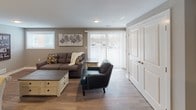 This thoughtfully designed single-floor unit offers a cohesive blend of modern finishes and comfortable living spaces. The open-concept kitchen is a standout feature, boasting dark espresso cabinetry that reaches to the ceiling, striking granite countertops, a central island, and a full suite of stainless steel appliances including a French door refrigerator, range, over-the-range microwave, and dishwasher. Warm hardwood-style flooring ties the kitchen seamlessly into the adjacent living area, where large vertical blinds over a sliding door and an additional window allow for generous natural light. The living space is welcoming and functional, with neutral taupe walls that carry throughout the unit. Two well-sized bedrooms offer plush carpeted floors, windows with exterior views, and ample room for furnishings. A stylish barn-style sliding door adds a contemporary touch leading to the bathroom, which features a large walk-in shower with chrome fixtures, wood-look flooring, and a clean, minimalist design. A dedicated closet space with built-in shelving provides excellent storage. The unit's consistent neutral palette, textured ceilings, and quality materials contribute to a polished and comfortable overall ambiance.