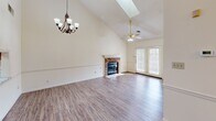 Located at 9001A NW Creekside Ln in Knoxville, Tennessee, this two-story home offers a well-designed layout spread across two floors. The welcoming entrance features parquet hardwood flooring, a decorative arched doorway, and a chandelier overhead, with a carpeted staircase accented by a warm wood banister leading to the upper level.

The main living area impresses with soaring vaulted ceilings, a skylight, and a classic brick fireplace as the focal point. Hardwood-style flooring, a ceiling fan, and French doors that invite natural light complete the space. The kitchen is well-equipped with warm oak cabinetry, granite-look countertops, stainless steel appliances including a refrigerator, dishwasher, and range, plus a skylight that brightens the room.

The spacious primary bedroom includes hardwood-style floors, a ceiling fan, a walk-in closet, and an en-suite bathroom featuring a jetted soaking tub beneath a window. Additional bedrooms are carpeted and include closet space. The upper floor offers a cozy bedroom with plush carpet and a built-in closet.

An attached garage with an automatic opener provides convenient parking and storage. Throughout the home, neutral tones and classic architectural details create a comfortable, functional living environment.