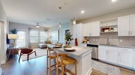 Located at 10210 Falcon Gate Loop in Riverview, Florida, this thoughtfully designed single-story residence offers a seamless blend of modern style and comfortable living. The open-concept kitchen is a standout feature, showcasing crisp white shaker cabinetry, granite countertops, a classic subway tile backsplash, and a full suite of stainless steel appliances. A central island with seating provides an ideal space for casual dining and entertaining, while pendant lighting adds a polished touch overhead. The kitchen flows naturally into the living area, which is bright and welcoming, with wood-style flooring, a ceiling fan, and windows that invite natural light. The primary bedroom is a serene retreat, featuring a ceiling fan, soft accent wall, and direct access to an en-suite bathroom equipped with a walk-in glass-enclosed shower with tile surround. A second bedroom offers a similarly comfortable atmosphere with ample natural light. The secondary bathroom includes a tiled tub-shower combination, granite vanity, and wood-style flooring. Throughout the residence, a consistent neutral color palette, wood-style flooring, and modern fixtures create a cohesive and contemporary ambiance suited to everyday living in Riverview, FL.