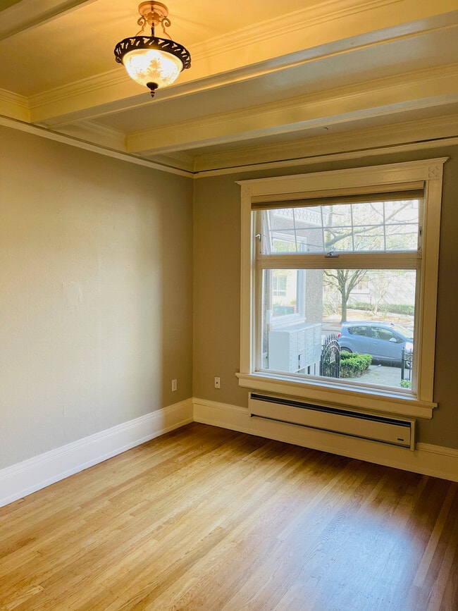 Comfortable bedroom with box beam ceiling and large window with cellular shades - 1205 Spring St
