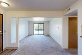 Located at 5800 Benson Dr in Haslett, Michigan, this single-floor residence offers two bedrooms and two bathrooms within a well-organized floor plan. The combined living and dining area forms the heart of the home, anchored by plush carpeting, a ceiling fan with light fixture, and a sliding glass door that fills the space with natural light and provides outdoor access. A pass-through window with a granite-style counter connects the living area to the kitchen, which features warm wood cabinetry, a tile-style floor, and functional counter space. The hallway links the main living areas to the private quarters, lined with an impressive seven closets that offer exceptional storage throughout. The primary bedroom is generously sized, bathed in natural light from a large window with vertical blinds, and finished with soft carpeting. The second bedroom is equally comfortable, with its own closet and easy access to the hallway. Both bathrooms are clean and functional, with one featuring wood-look tile flooring, a bathtub, and classic white fixtures. The consistent use of neutral tones, warm wood door accents, and carpeted floors throughout creates a cohesive and practical living environment.