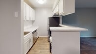 Located at 6060 Reserve Dr. in Charlotte, NC, this single-floor residence offers a well-organized layout with thoughtfully updated interiors throughout. The kitchen is designed for functionality, featuring white shaker-style cabinetry, marble-look countertops, stainless steel appliances, and wood-look flooring that ties the space together with a clean, contemporary aesthetic. A pass-through counter connects the kitchen to the main living area, creating an open and communicative flow between the two spaces. The living area is generously proportioned, highlighted by rich, dark wood-look flooring, neutral gray walls, and a ceiling fan for year-round comfort. Natural light filters in through windows fitted with horizontal blinds, lending the space a bright yet private atmosphere. The bedroom offers a comfortable retreat with soft carpeting, neutral wall tones, and a window with outdoor views of the surrounding greenery. The bathroom is well-appointed with a full tub and shower combination, white tiled surround, a vanity with storage, and wood-look flooring that complements the rest of the home. Clean lines and a cohesive neutral color palette unify each room, making this Charlotte residence a practical and inviting space.