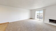 Located at 1300 NW Candletree Dr in Blue Springs, MO, this well-appointed 2-bedroom, 3-bathroom unit offers a thoughtfully designed single-level layout. The galley-style kitchen is a standout feature, showcasing white shaker cabinetry, granite-look countertops, a stainless steel sink, and a full suite of stainless steel appliances including a range, microwave, and refrigerator, all set atop durable light wood-look flooring. A connecting hallway with the same flooring links the kitchen to the rest of the unit seamlessly. The spacious living area is carpeted and bathed in natural light, with a sliding glass door opening to a private balcony with outdoor views. Both bedrooms are comfortably sized, featuring plush carpeting and sliding closet doors for ample storage. The generously sized primary bedroom provides a comfortable retreat. The bathrooms include a clean, functional design with a wood-toned vanity, white countertop, mirror, and tub/shower combo with built-in shelving. Light wood-look tile flooring carries through the bathrooms and hallway, creating a cohesive flow throughout the unit. Bright white walls and natural light give the entire space a clean, airy ambiance.