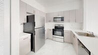 Located at 1451 W 29th St in Hialeah, FL, this thoughtfully designed one-bedroom, one-bathroom unit offers a clean, contemporary aesthetic throughout. The entire unit is finished with polished marble-look tile flooring that reflects light and lends a bright, airy feel to every room.

The open-concept living and kitchen area forms the heart of the unit. The kitchen is well-appointed with sleek, taupe cabinetry extending to the ceiling for ample storage, white quartz countertops, and a full suite of stainless steel appliances including a refrigerator, electric range, and microwave. A peninsula counter separates the kitchen from the living area, creating a natural flow between the two spaces.

The bedroom is a comfortable, light-filled room featuring a window with views of the surrounding building exterior, two closets for generous storage, and clean white walls that keep the space feeling open and calm.

The full bathroom is finished in the same marble-look tile and includes a tub-shower combination, a vanity with cabinet storage, a large mirror, and overhead lighting. A dedicated laundry area and utility room add everyday convenience, while the private balcony provides a welcome outdoor retreat. Recessed lighting throughout the unit completes its modern, move-in-ready presentation.