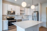 Located at 3900 Monona Dr in Madison, Wisconsin, this thoughtfully designed one-bedroom, one-bathroom residence offers a comfortable and modern living experience on a single floor. Light wood flooring flows consistently throughout the space, contributing to a warm, cohesive aesthetic.

The kitchen is a standout feature, boasting white shaker cabinetry accented with gold hardware, a marble-style tile backsplash, and a suite of stainless steel appliances including a refrigerator, electric range, and microwave. A central island with a crisp white countertop provides additional prep space and connects seamlessly to the open living area. Globe pendant lights add a stylish touch overhead.

The living room is bright and airy, with large windows that invite generous natural light and offer views of the surrounding neighborhood. A door leads to a private balcony, further enhancing the connection to the outdoors.

The bedroom is a well-proportioned retreat featuring a ceiling fan, a closet with built-in shelving, and a window that continues the theme of natural light throughout the unit.

The bathroom is clean and modern, with a wide vanity, white countertop, gold-accented cabinetry, a large mirror, and a shower/tub combination with matte black fixture accents completing the space.