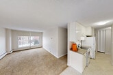 Located at 10159 118 St NW in Edmonton's vibrant Oliver neighbourhood, this 2-bedroom, 1-bathroom unit offers a practical and well-organized single-floor layout. The open-concept living and dining area is generously sized, featuring wall-to-wall carpet and a large window that floods the space with natural light while framing views of the surrounding Edmonton skyline. The kitchen is positioned adjacent to the living area and includes white cabinetry reaching to the ceiling for ample storage, a full-size refrigerator, and a stove, with light tile flooring that contrasts neatly with the carpeted living spaces. A hallway connects the main living area to the two bedrooms, each carpeted and finished in neutral tones. The primary bedroom is comfortably sized with a window offering city views and baseboard heating. The second bedroom also features carpet and accordion-style closet doors. Six closets are distributed throughout the unit, providing exceptional storage capacity. The bathroom features a full tub-shower combination with classic tiled surround in a checkerboard pattern, complemented by neutral finishes. Baseboard heating is present throughout, and textured ceilings add a subtle architectural detail to the overall interior.