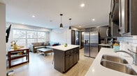 Located at 1625 Marshall Ave in Saint Paul, MN, this 2-bedroom, 2-bathroom unit offers a thoughtfully designed single-floor layout that maximizes its efficient footprint. The open-concept kitchen and living area serves as the heart of the space, anchored by a central island with a white quartz countertop and seating. The kitchen features dark, richly stained cabinetry, a classic white subway tile backsplash, stainless steel appliances including a large French-door refrigerator, and ample upper and lower storage. Recessed lighting and two pendant lights above the island create a warm, functional atmosphere. The adjoining living area is bathed in natural light from a large window, lending an airy quality to the shared space. Light-toned luxury vinyl plank flooring runs consistently throughout, unifying each room. Both bedrooms offer closet storage and windows with street views. The primary bedroom includes a private en-suite bathroom, while a second full bathroom serves the additional bedroom and guests. Both bathrooms are finished with dark wood vanities, white countertops, and framed mirrors, maintaining a cohesive modern aesthetic. A dedicated dining nook with natural light provides additional versatility to the layout.
