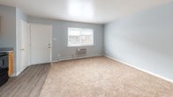 Located at 2530 Marina Dr in North Chesterfield, Virginia, this single-floor unit offers a straightforward and functional layout designed for comfortable everyday living. The living area is carpeted in warm beige tones and painted in soft light blue, creating a calm and neutral atmosphere. A window along the front wall allows natural light to fill the space, accompanied by a wall-mounted HVAC unit and baseboard heating for year-round comfort. The entry door opens directly into this main living area, providing easy access.

The kitchen features warm oak cabinetry with ample upper and lower storage, gray laminate countertops, a stainless sink, and black appliances including a refrigerator, electric range, and overhead ventilation hood. Durable wood-look vinyl flooring grounds the kitchen space and provides a practical transition from the carpeted living areas.

The bedrooms continue the light blue color palette with plush carpeting underfoot. Ceiling fans with integrated lighting fixtures are present in the bedrooms, offering both air circulation and ambient light. One bedroom includes an access panel on the wall, and natural light enters through windows with views of the surrounding brick exterior buildings.

The bathroom is outfitted with a full-sized soaking tub and shower combination, accented by classic yellow subway tile walls and black tile border trim, lending the space a retro, vintage character.