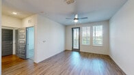 Located at 10387 Vista Oaks Ct in Orlando, FL, this well-appointed 2-bedroom, 2-bathroom residence offers a thoughtfully designed single-floor layout with a bright, open-concept living area. The combined living, dining, and kitchen space is the heart of the home, anchored by a large granite-topped island with pendant lighting overhead. The kitchen is outfitted with white shaker-style cabinetry, a subway tile backsplash, and a full suite of stainless steel appliances including a refrigerator, range, microwave, and dishwasher. Wood-style flooring flows throughout the main living areas, complemented by neutral tones and abundant natural light from large windows and a balcony-access door fitted with modern blinds. A ceiling fan anchors the living room, which opens directly to the private balcony with outdoor views of lush greenery. The primary bedroom features direct balcony access, a ceiling fan, and plush carpeting, while the en suite bathroom includes a granite vanity, LED-lit mirror, and a glass-enclosed walk-in shower with tile surround. The secondary bedroom is carpeted and bright. Five closets provide generous storage throughout. A dedicated laundry area and a connecting hallway round out this well-organized and move-in-ready residence.