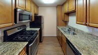 Located at 750 Paseo De Luz in Chula Vista, this single-floor unit offers a well-organized layout with a cohesive and comfortable design throughout. The living area is spacious and bathed in natural light, featuring rich wood-look flooring and neutral warm-beige walls that create a welcoming atmosphere. A sliding glass door with vertical blinds opens the living space to the outdoors, allowing for excellent natural light and ventilation.

The galley-style kitchen is efficiently designed, with warm-toned wood cabinetry lining both sides and providing generous storage. Granite countertops add a polished touch, while black appliances — including a gas range, microwave, refrigerator, and dishwasher — complete the functional setup. The wood-look flooring continues seamlessly from the living area into the kitchen.

The bedroom features plush wall-to-wall carpeting and a window fitted with horizontal blinds, offering a quiet and comfortable retreat with a glimpse of greenery outside. The bathroom is clean and straightforward, equipped with a full-size soaking tub and shower combination with crisp white surrounds and tile flooring. Additional hallway space connects the rooms with recessed lighting, maintaining the unit's bright and open feel throughout.