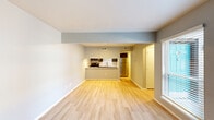 This two-floor residence is designed with a clean, contemporary aesthetic characterized by neutral wall tones, light-colored flooring, and a practical layout that maximizes functionality. The entry opens into a bright, open living area finished with light hardwood-style flooring and large windows fitted with horizontal blinds, allowing natural light to flow freely into the space.

The kitchen is positioned adjacent to the living area and features a pass-through breakfast bar that connects the two spaces. Dark cabinetry contrasts with a white subway tile backsplash, while stainless steel appliances—including a refrigerator, range, microwave, and dishwasher—provide a modern, cohesive finish. The kitchen is fully accessible from a dedicated side corridor, offering additional functionality and ease of use.

The bedrooms are carpeted and present a comfortable, quiet atmosphere. Each room benefits from natural light via windows with blinds. At least one bedroom includes a spacious walk-in closet equipped with dual hanging rods and carpeted flooring, providing ample storage capacity.

Throughout the residence, consistent design choices—including white trim, recessed and flush-mount lighting, and a neutral color palette—create a cohesive and move-in ready environment across both floors.