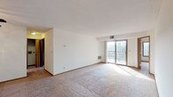 This single-floor residence offers a functional and comfortable layout across several well-defined spaces. The living room is generously proportioned, featuring neutral carpet, white walls, and a sliding glass door that opens to a private balcony with outdoor views of surrounding greenery, allowing abundant natural light to fill the room. A ceiling fan with a light fixture is positioned near the entryway, which features a wood-toned front door.

The kitchen is well-appointed with warm oak cabinetry offering ample storage, granite-look countertops, and a full suite of stainless steel appliances including an electric range, dishwasher, refrigerator, and a stainless sink. Light hardwood-style flooring completes the space.

The two bedrooms are carpeted and each features a ceiling fan with lighting, a closet with a wood-panel door, and windows overlooking tree-lined outdoor scenery. Both rooms are bright and offer comfortable proportions.

Two bathrooms mirror each other in design, each featuring a wide vanity with an integrated sink, light-toned cabinetry, a large mirror with overhead globe lighting, chrome towel bars, and tile flooring, providing a clean and practical aesthetic throughout.