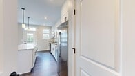 Located at 305 Timberland Drive in Ann Arbor, Michigan, this thoughtfully designed 2-bedroom, 1-bathroom single-floor home offers a clean, modern aesthetic throughout. The open-concept kitchen and living area serves as the heart of the home, featuring white shaker cabinetry with matte black hardware, granite countertops, stainless steel appliances, and rich dark hardwood flooring. Natural light pours in through multiple windows, and a glass-panel door provides direct access to a private balcony overlooking the surrounding neighborhood. The bathroom continues the home's contemporary style with a granite-topped vanity, white cabinetry, matte black fixtures, and a glass-enclosed shower. The primary bedroom offers a comfortable footprint with recessed lighting, while a dedicated walk-in closet provides built-in shelving and hanging storage. The second bedroom features plush carpeting, a ceiling fan, and large windows that invite ample natural light and neighborhood views. Neutral wall tones, clean white trim, and consistent finishes throughout create a cohesive and inviting atmosphere. A hallway connects all rooms efficiently, completing this well-organized and move-in-ready home.