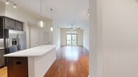 Located along NASA Parkway in Houston, TX, this well-appointed one-bedroom, two-bathroom residence offers a thoughtfully designed single-floor layout. The open-concept living and kitchen area features warm hardwood flooring throughout, with a ceiling fan and sliding glass doors that lead to a private balcony overlooking lush greenery and the surrounding community.

The kitchen is a standout feature, showcasing rich dark-stained cabinetry, granite countertops, a classic subway tile backsplash, and a full suite of stainless steel appliances including a gas range, built-in microwave, refrigerator, and dishwasher. A kitchen island with a white countertop adds additional prep space and a clean contrast to the cabinetry.

The spacious primary bedroom is carpeted for comfort, equipped with a ceiling fan, and features a large window with views of mature trees. It connects to a generous walk-in closet outfitted with multi-level wire shelving and hanging rods. The en-suite primary bathroom is elegantly finished with floor-to-ceiling marble-style tile, a soaking corner tub, a glass-enclosed walk-in shower, and a vanity with a granite countertop. A second bathroom provides additional convenience for guests.