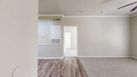 This single-floor, one-bedroom, one-bathroom unit offers a practical and cohesive layout designed to maximize every square foot of its compact footprint. The living area features warm wood-look vinyl flooring, neutral beige walls, and crown molding, creating a clean and inviting atmosphere. An HVAC unit is conveniently integrated into the living space wall, ensuring year-round comfort.

The galley-style kitchen is efficiently designed with light wood cabinetry, granite-look countertops, and a full suite of stainless steel appliances, including a refrigerator, range, and dishwasher. Recessed lighting illuminates the kitchen, which opens toward a peninsula counter that connects to the main living area.

The bedroom is a comfortable, carpeted retreat featuring a ceiling fan, a window with natural light and exterior views, and ample wall space. An adjoining walk-in closet provides generous storage with wire shelving systems and wood-look flooring.

The bathroom includes a full tub-shower combo with white tile surround, wood-look vinyl flooring, light wood cabinetry, and a vanity with countertop storage. A dedicated laundry area rounds out the unit's functional offerings, making this a complete and well-equipped living space.