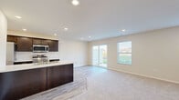 Located at 14703 Gul St. in the Copper Creek Villas community of Huntertown, Indiana, this two-story home offers a thoughtfully designed layout with clean, contemporary finishes throughout. The main level centers on an open-concept living and kitchen area, where light-toned walls and recessed lighting create a bright, welcoming atmosphere. The kitchen is well-appointed with dark espresso cabinetry, light countertops, stainless steel appliances including a refrigerator, range, microwave, and dishwasher, and a central island with a sink that overlooks the living space. Light wood-look flooring runs through the kitchen and transitions to plush neutral carpeting in the living area. A sliding glass door and an adjacent window allow natural light to flow in while providing direct access to the outdoors. Additional rooms on the upper level feature soft carpeting, neutral walls, and recessed lighting, offering versatile living spaces. A full bathroom includes a tub-shower combination with brushed nickel fixtures and clean white surrounds. The overall design presents a move-in-ready home with a cohesive, modern aesthetic suited for comfortable everyday living.