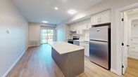 Located at 1100 Afton Dr in Windsor, Ontario, this well-appointed one-bedroom, one-bathroom unit offers a thoughtfully designed layout with modern finishes throughout. Light-toned luxury vinyl plank flooring flows seamlessly across the entire space, complementing the neutral warm-beige walls and crisp white trim.

The kitchen serves as a central highlight, featuring a two-tone island with a quartz-style countertop, white shaker cabinetry extending to the ceiling, a subway tile backsplash, and a full suite of stainless steel Whirlpool appliances including a refrigerator, electric range, and dishwasher. The open-plan layout connects the kitchen directly to the living area, which benefits from a sliding glass door leading to a private balcony with open outdoor views.

The bedroom is a calm, well-proportioned space with a large window that brings in natural daylight. A dedicated closet provides convenient storage. The bathroom is clean and functional, offering a full soaker tub and shower combination, a white vanity with quartz countertop, and a mirrored medicine cabinet.

A dedicated laundry room houses a full-sized Whirlpool washer and dryer set beneath a built-in countertop with an overhead wire shelf, adding exceptional practicality to this efficiently organized home.