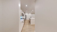 Located at 16 Congress Street in Beverly, MA, this thoughtfully designed 2-bedroom, 2-bathroom residence offers a clean, contemporary aesthetic throughout. Light-toned hardwood flooring runs seamlessly across the entire unit, complementing the neutral palette of soft white and greige walls accented by crisp white baseboards.

The open-concept kitchen and living area serves as the heart of the home. The kitchen is outfitted with two-tone cabinetry — white lower cabinets paired with light wood upper cabinets — complemented by a classic white subway tile backsplash, quartz countertops, a central island with an undermount sink, and a full suite of stainless steel appliances. Recessed lighting illuminates the space throughout. The living area features sliding glass doors that open to a private balcony with outdoor views.

Both bedrooms are well-proportioned and filled with natural light from blinds-fitted windows. The primary bedroom benefits from a wall-mounted split HVAC unit for year-round comfort.

The two bathrooms are finished with a modern sensibility. One features a deep soaking tub with built-in shelving and matte black fixtures, while the other showcases a striking grid-patterned glass shower enclosure with matching black hardware. A dedicated closet rounds out the functional layout of this well-appointed residence.