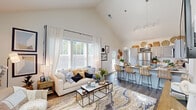 Located at 388 Hinson Dr in Myrtle Beach, SC, this single-story home is defined by its striking vaulted ceilings and open-concept design, creating a sense of expansive, airy living. The main living area is bathed in natural light from large windows dressed with sheer white curtains, illuminating the soaring ceiling lines and wood-look flooring that run throughout. The living room offers generous space for comfortable seating arrangements, anchored by a statement area rug in warm, earthy tones.

The kitchen flows seamlessly from the living space and features grey cabinetry paired with crisp white countertops, stainless steel appliances, and a large peninsula with bar seating—ideal for casual dining or entertaining. A globe pendant light adds a modern focal point above the counter.

The bedroom is comfortably proportioned with a ceiling fan, natural light from well-placed windows, and direct access to an en suite bathroom. The bathroom includes grey vanity cabinetry, white quartz countertops, a bold-framed mirror, and louvered closet doors leading to additional storage. A walk-in closet with wire shelving provides practical organization. A dedicated entryway with additional shelving and storage completes this well-designed home.