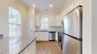 Located at 342 Fife Way in Myrtle Beach, South Carolina, this single-story home presents a clean, modern aesthetic with consistent finishes and attention to detail throughout. The open layout connects living areas seamlessly, with warm hardwood-style flooring running through the main spaces and a neutral color palette that enhances the sense of openness.

The kitchen is a standout feature, equipped with crisp white shaker-style cabinetry extending to the ceiling, granite countertops, a subway tile backsplash, and a full suite of stainless steel appliances including a refrigerator, range, microwave, and dishwasher. A peninsula with pendant lighting provides additional workspace and connects the kitchen to the living area, which benefits from multiple windows and a ceiling fan overhead.

The bedrooms offer comfortable proportions with tall ceilings, large windows that invite natural light, hardwood-style flooring, and closet storage. A wide hallway with tall ceilings connects the rooms, adding to the home's open feel.

The bathrooms are finished with white cabinetry, granite countertops, and light tile flooring. One bathroom features a glass-enclosed shower, while another includes a tub and shower combination. Crown molding and recessed lighting appear throughout, adding refined touches to the overall design.