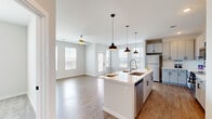Located in the sought-after Grand Cordera neighborhood of Colorado Springs, CO, this well-designed single-floor home offers three bedrooms and two bathrooms across a comfortable and efficiently laid-out floor plan. The entrance leads through a bright, clean hallway accented by arched doorways and warm hardwood-style flooring, guiding you into the heart of the home. The open-concept kitchen and living area is a standout feature, boasting a central island with a undermount sink, sleek white cabinetry, stainless steel appliances, and stylish pendant lighting. Multiple windows bathe the space in natural light, while a ceiling fan adds comfort to the living area, which also offers access to the outdoors. The bedrooms are carpeted for warmth and comfort, each equipped with a ceiling fan and windows with views of the surrounding neighborhood. The spacious primary bedroom connects to an en-suite bathroom featuring marble-style tile in a glass-enclosed shower, a white vanity, and direct access to a walk-in closet with built-in shelving. The secondary bathroom includes a full tub and shower with elegant marble-style tile surround. Additional closets and hallways complete this clean, modern home.