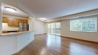 This single-floor residence offers a thoughtfully designed layout that balances open communal spaces with comfortable private areas. The living room serves as the heart of the home, featuring warm light hardwood flooring, a textured ceiling, and generous natural light streaming through large sliding glass doors that open directly onto a private outdoor deck — an ideal spot for enjoying wooded outdoor views.

The kitchen is well-equipped for everyday living, showcasing warm honey-toned wood cabinetry with ample upper and lower storage, light countertops, and a full suite of stainless steel appliances including a refrigerator, dishwasher, electric range, and over-the-range microwave. The kitchen connects seamlessly to the living area via a convenient pass-through, enhancing the open-concept feel.

The bedrooms are finished with plush carpeting and neutral walls, providing a calm and restful atmosphere. At least one bedroom benefits from a dedicated walk-in closet with built-in shelving. The bathroom is appointed with a wood-toned vanity, a large mirror, and a full bathtub and shower combination set against clean white surrounds, complemented by hardwood-style flooring.

A dedicated in-unit laundry area houses a full-sized washer and dryer with overhead wire shelving for added storage convenience. Throughout the residence, warm wood tones, consistent finishes, and practical design choices create a cohesive and inviting living environment.
