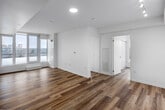 Located at 2376 Dundas Street West in Toronto's vibrant Junction neighbourhood, Unit 717 is a well-appointed two-bedroom, one-bathroom suite designed with a clean, contemporary aesthetic. Light wood-tone flooring runs consistently throughout the unit, complementing the bright white walls and creating a cohesive, modern feel.

The entrance hallway features a sliding storage closet and leads into the open-concept kitchen and living area. The kitchen is efficiently designed with flat-front white cabinetry extending to the ceiling, a white subway tile backsplash, light countertops, and a full suite of stainless steel appliances including a dishwasher, electric range, over-the-range microwave, and refrigerator. Track lighting overhead adds functional illumination to the cooking space.

Both bedrooms benefit from generous window coverage, with large floor-to-ceiling windows offering expansive city views and access to a shared balcony. The primary bedroom features a corner window configuration, maximizing natural light and providing panoramic sightlines across the Toronto skyline.

The bathroom is finished with large-format grey wall tiles surrounding a full soaker tub and shower, complemented by a white vanity and clean fixtures. Throughout the unit, the bright, neutral palette and abundant natural light contribute to an airy and functional living environment.