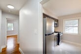 Located at 2 Manchester Pl, Unit 3C in Newark, NJ, this one-bedroom, one-bathroom residence offers a well-designed layout across a single floor. Rich hardwood flooring flows throughout the living areas and bedroom, lending warmth and character to the space. The open-concept kitchen and living room area is thoughtfully arranged, with the kitchen featuring dark cabinetry accented by gold hardware, gleaming white countertops, polished marble-style tile flooring, stainless steel appliances including a gas range and microwave, and a window that brings in natural light. The spacious living area connects seamlessly to the rest of the unit via a hallway with crisp white panel doors and matte black hardware. The generously sized primary bedroom is filled with natural light from two large windows offering outdoor views, and is equipped with a baseboard radiator for comfortable heating. A modern multi-light chandelier adds a contemporary touch. The bathroom is a standout feature, showcasing floor-to-ceiling marble-style tile surrounding a soaking tub with an integrated shower, matte black fixtures, a dark vanity with glass-front cabinet doors, and a framed mirror. Neutral gray walls throughout the unit create a clean, cohesive aesthetic ideal for comfortable everyday living.