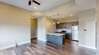 Located at 34 W Federal St in downtown Youngstown, Ohio, this well-appointed 5-bedroom, 2-bathroom unit offers a thoughtfully designed single-floor layout with a clean, modern aesthetic throughout. The open-concept living, dining, and kitchen area serves as the heart of the home, featuring rich hardwood-style flooring, recessed lighting, and a ceiling fan. The kitchen is equipped with stainless steel appliances, dark espresso cabinetry, a peninsula island with a light stone countertop and pendant lighting, making it both functional and stylish. Connecting hallways are lined with white panel doors and accented with dark hardware, maintaining a consistent design language across the unit. The five bedrooms offer a mix of hardwood-style and carpeted flooring, with several rooms featuring large windows that frame views of the Youngstown cityscape. The spacious primary bedroom includes its own ceiling fan and generous natural light. Four closets provide ample storage, including walk-in options with wire shelving systems. The two bathrooms are finished with neutral tile flooring, wood-toned vanities, and full tub-shower combinations. A dedicated laundry area and entrance complete this well-rounded, move-in-ready unit in the heart of downtown Youngstown.