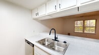 Located at 4047 Woodland Creek Dr SE in Kentwood, Michigan, this single-floor home offers a clean, modern aesthetic throughout its well-organized layout. The kitchen is a functional highlight of the space, featuring white shaker-style cabinetry with matte black hardware, sparkling quartz countertops, a double stainless steel sink paired with a sleek black pull-down faucet, a gas range, stainless steel dishwasher, and a full-size refrigerator. Light wood-look flooring runs through the kitchen and main living areas, lending warmth and continuity to the space. The open layout connects the kitchen to the adjoining living area, which benefits from natural light filtering through a window. The bedrooms are finished with plush neutral carpeting and are bright, thanks to multiple windows dressed with white horizontal blinds. One carpeted room includes a closet with paneled sliding doors, providing practical storage. An additional room with light wood flooring offers versatility and is bathed in natural light from a side window. Throughout the home, crisp white walls, clean trim work, and consistent neutral tones create a bright, move-in-ready atmosphere that is both welcoming and easy to personalize.