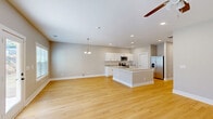 Located at 3 Halcyon Ln in Newnan, Georgia, this two-story, 4-bedroom, 4-bathroom home offers a well-designed layout spread across two floors. The main level features an open-concept living and dining area that flows seamlessly into a modern kitchen. The kitchen is equipped with white cabinetry, granite countertops, stainless steel appliances including a side-by-side refrigerator and dishwasher, and a central island. Light hardwood flooring runs throughout the main level, complemented by recessed lighting and a chandelier over the dining area. A glass-panel door and large windows invite natural light and provide views of the outdoors. A carpeted staircase leads to the upper level, where all four bedrooms are located. Each bedroom features plush carpet flooring, ceiling fans, and ample closet space with double-door closets. The generously sized primary bedroom includes an ensuite bathroom with granite vanity countertops and hardwood flooring. The eight closets throughout the home offer abundant storage. A dedicated laundry room and an attached garage add everyday convenience. Neutral warm-gray tones carry throughout both floors, creating a clean, cohesive, and move-in-ready atmosphere.