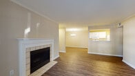 This single-floor residence offers a well-organized layout that connects living, dining, and kitchen spaces in an open, cohesive flow. The living room serves as the central gathering area, highlighted by a classic white-mantled fireplace with tile surround and hearth, complemented by rich hardwood-style flooring. Crown molding adds a refined architectural detail throughout the main living areas. A glass door in the living room opens directly to a private outdoor patio, allowing natural light to fill the space and providing convenient outdoor access.

Adjacent to the living room, the dining area features an elegant chandelier and flows seamlessly toward the kitchen, which is accessible via a pass-through counter. The galley-style kitchen is efficiently designed with white cabinetry lining both sides, light-toned countertops, a stainless steel sink, and white appliances, including a refrigerator and stove. Recessed and overhead lighting keeps the kitchen bright and functional.

The bedrooms are comfortably appointed with wall-to-wall carpeting, ceiling fans with light fixtures, and windows with blinds that allow for natural light. The bathroom includes a full soaking tub and shower combination with brushed gold fixtures, a white surround, and a vanity with mirror. Throughout the unit, warm neutral wall tones create a consistent and inviting ambiance.