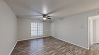 Located at 1002 Edmonds Lane in Lewisville, TX, this one-bedroom, one-bathroom unit offers a well-organized single-floor layout designed to maximize functionality. Wood-look plank flooring runs throughout the entire space, providing a cohesive and low-maintenance aesthetic. The open living room serves as the central gathering area, featuring a ceiling fan with light kit, neutral gray walls, and a large window with blinds that invites natural light. The galley-style kitchen is equipped with warm oak cabinetry, light granite-style countertops, a double stainless steel sink, and a full suite of black appliances including a refrigerator, electric range, microwave, and dishwasher. A peninsula counter connects the kitchen to the hallway, offering additional workspace and an open sightline toward the living area. The bedroom provides a comfortable and private retreat, complete with its own ceiling fan, a window for natural light, and direct access to a dedicated closet. The bathroom features a full tub-shower combination, a wooden vanity with a granite-style countertop, and wood-look flooring that ties into the rest of the unit. A hallway connects all areas efficiently, completing this practical and well-appointed layout.