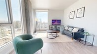 Located at 830 Eddy Street in San Francisco's Lower Nob Hill neighborhood, this rooftop terrace offers a thoughtfully designed outdoor retreat with sweeping 360-degree views of the San Francisco skyline, the distant hills, and beyond. The terrace is finished with large-format stone tiles that lend a clean, modern aesthetic throughout the generous open-air space.

A standout feature is the vibrant red high-top bar station, complete with matching red barstools, which serves as a bold social focal point against the backdrop of the downtown skyline—including a glimpse of the Transamerica Pyramid. Surrounding the bar area, raised Cor-Ten steel planters are filled with a diverse mix of trees, palms, succulents, and flowering plants, adding warmth, texture, and a lush, garden-like atmosphere.

The terrace is organized into multiple distinct zones: a casual lounge area furnished with comfortable outdoor sofas and coffee tables, a dining area with bistro-style tables and chairs shaded by mature trees, and open promenades ideal for entertaining or relaxed strolling. Low-profile living green walls and ground-level planted beds line the perimeter, softening the boundary walls while contributing to the space's verdant character.

Recessed step lighting is integrated throughout, ensuring the terrace is equally inviting after dark. The result is a well-appointed, multi-functional outdoor space designed for community gathering and urban enjoyment.