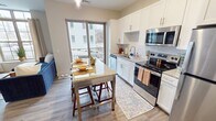 This well-designed 520 square foot apartment maximizes space efficiency while offering modern comforts. The open-concept layout seamlessly integrates the kitchen, living, and dining areas, creating a sense of spaciousness. The kitchen boasts white cabinetry, granite countertops, and stainless steel appliances, including a full-sized refrigerator and built-in microwave. A small dining table adjacent to the kitchen provides a cozy eating nook.

The living area features wood-look flooring, a ceiling fan, and a large window that floods the space with natural light. Stylish blue accent furniture adds a pop of color to the neutral palette. The bedroom, measuring 120 square feet, includes a queen-sized bed, nightstands, and ample closet space with wire shelving. The bathroom showcases a granite vanity top, modern fixtures, and a combination of open and closed storage.

Throughout the apartment, recessed lighting and contemporary light fixtures enhance the modern aesthetic. The cohesive design elements, including consistent flooring and paint colors, create a harmonious flow between rooms. Despite its compact size, this apartment offers a comfortable and functional living space with attention to detail in its finishes and layout.
