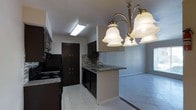 This multi-floor space spans three levels, offering a versatile and functional layout throughout. The kitchen is a standout feature, showcasing dark espresso cabinetry that provides generous storage alongside granite countertops and a decorative mosaic tile backsplash that adds texture and visual interest. A built-in black appliance suite, including a range and dishwasher, contributes to a cohesive, modern aesthetic. The kitchen flows naturally into an adjacent living or dining area by way of a peninsula counter with an undermount sink, making it ideal for both everyday use and entertaining. An elegant brass and frosted glass chandelier hangs above the transition space, casting warm, ambient light and serving as a charming focal point. Light-toned tile flooring runs throughout the kitchen and adjoining areas, reflecting the overhead lighting and contributing to a bright, open feel. The neutral wall tones throughout provide a clean, versatile backdrop. With three floors of living space, this property offers ample room for a variety of uses, combining practical design with thoughtful details across every level.