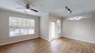 Located at 9600 Coit Rd in Plano, Texas, this single-floor residence offers a well-designed layout with a cohesive blend of comfort and functionality. The open living area is finished with warm wood-style flooring, crown molding, and neutral-toned walls that create a bright and welcoming atmosphere. Large windows with blinds allow ample natural light to fill the space, while ceiling fans provide year-round comfort. A track lighting fixture adds a modern accent to the living area.

The kitchen is a standout feature, showcasing warm honey-toned cabinetry, granite countertops, a subway tile backsplash, and stainless steel appliances including a range, microwave, and refrigerator. A central island with a built-in sink and pendant lighting above serves as both a functional workspace and a casual gathering point. The kitchen flows seamlessly into the living area, enhancing the open-concept feel.

The bedrooms are carpeted for added comfort, each equipped with ceiling fans and window access to natural light. One bedroom includes an adjoining closet area. The bathroom features a tiled tub-shower combination with chrome fixtures and hardwood-style flooring. A dedicated in-unit laundry area houses a full-size washer and dryer, adding everyday convenience to this well-appointed Plano residence.