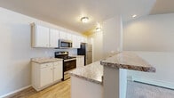 Located at 2124 Kennedy Dr in New Holstein, Wisconsin, this two-story residence offers three bedrooms, two full bathrooms, and a thoughtfully organized layout spread across two floors. The main level provides a compact yet functional entry point, while the upper floor houses the majority of the living space, including the primary living areas and bedrooms.

The open-concept kitchen and dining area is a highlight of the upper floor, featuring white cabinetry, granite-style countertops, stainless steel appliances including a range, microwave, and refrigerator, and light wood-style flooring that adds warmth throughout. A peninsula countertop provides additional prep space and a natural divider between the kitchen and the adjoining living room, which is finished with plush carpeting.

The generously sized primary bedroom offers ample room and includes a wall-mounted air conditioning unit and baseboard heating. The additional bedrooms are carpeted and well-proportioned. Both bathrooms are finished with white cabinetry, granite-style vanity tops, and wood-style tile flooring, with one featuring a shower-tub combination. A dedicated laundry room with wire shelving adds everyday convenience. Sliding glass doors open to a private balcony with exterior views, and carpeted staircases connect the two levels seamlessly.