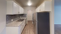 Located at 1919 Silver Bell Rd in Eagan, Minnesota, this single-floor residence offers a thoughtfully designed layout with a range of updated finishes and functional spaces. The galley-style kitchen is a standout feature, showcasing white shaker cabinetry with brushed nickel hardware, granite-look countertops, a gray subway tile backsplash, stainless steel appliances, and durable wood-look flooring — creating a clean, modern aesthetic. Adjacent to the kitchen, the open living and dining areas offer a smooth transition between spaces, with warm carpet in the living room and wood-look flooring in the dining area, illuminated by a pendant light fixture. The bedroom is generously sized with plush carpeting, a window with natural light, a wall-mounted AC unit, and baseboard heating. A spacious walk-in closet with wire shelving provides ample storage. The primary bathroom features a tub-shower combination with white tile surround and mosaic tile flooring, while a separate vanity area includes a wide mirror and white cabinetry. A private water closet with tile flooring adds an extra layer of convenience. Throughout the unit, neutral tones and clean lines create a bright, move-in-ready atmosphere.