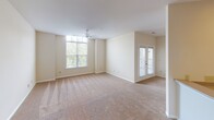 Located at 13912 Cedar Farm Rd in Charlotte, NC, this single-story home offers a clean, neutral aesthetic throughout its thoughtfully laid-out floor plan. The interior is finished with warm beige tones and plush carpeting across the main living and bedroom areas, creating a cohesive and comfortable feel.

The expansive living area is a standout feature, benefiting from a large multi-pane window that draws in generous natural light, complemented by a ceiling fan overhead. French doors provide direct outdoor access, further enhancing the bright, open atmosphere of the space.

The kitchen is outfitted with warm wood-toned cabinetry extending to the upper walls, offering substantial storage. Speckled laminate countertops provide functional workspace, and black appliances — including an electric range and over-the-range microwave — complete the setup.

The bedrooms are carpeted and well-proportioned, each featuring blinds-fitted windows that allow for controlled natural light. The bathrooms include tile flooring, a vanity with stone-finish countertops, white cabinetry, and a glass-enclosed walk-in shower. One bathroom also features convenient access to a walk-in closet. The entry foyer is finished with diagonal-set tile flooring, offering a welcoming transition into the home.