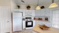 This two-story home offers a thoughtfully designed layout with a variety of functional and comfortable living spaces. The kitchen is well-appointed with white cabinetry, light countertops, tile flooring, a gas range, built-in microwave, and a full-size refrigerator. A pendant light fixture adds a warm focal point, while generous cabinet storage keeps the space organized and practical. Adjacent to the kitchen, the dining area benefits from a large window fitted with horizontal blinds, allowing natural light to fill the room and offering views of the surrounding neighborhood. Crown molding adds a refined architectural detail to this space. The living room features carpeted flooring, neutral walls, and a distinctive arched niche — a charming architectural accent that adds character to the room. A ceiling fan is present in the bedroom, which is carpeted and includes dual closets with arched panel doors, providing substantial storage. The full bathroom is finished with tile flooring, a single-sink vanity with white cabinetry, and a tub-shower combination. The attached garage offers a spacious, clean concrete floor area with an automatic garage door opener. Throughout the home, a neutral color palette and consistent finishes create a cohesive and welcoming atmosphere.