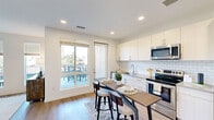 Located at 66 S Van Gordon St in Lakewood, Colorado, this one-bedroom, one-bathroom residence offers a thoughtfully designed single-level layout with modern finishes throughout. The open-concept kitchen and living area serves as the heart of the home, featuring white shaker-style cabinetry, a classic subway tile backsplash, stainless steel appliances including a range, microwave, and refrigerator, and a built-in dining bar with seating. Light wood-style flooring extends throughout the entire space, creating a cohesive and contemporary feel. A sliding glass door in the kitchen/living area leads directly to a private outdoor balcony, flooding the interior with natural light and providing outdoor views of the surrounding Lakewood neighborhood. The living room includes large windows with blinds, further enhancing the bright and airy ambiance. The bedroom is a comfortable retreat with a ceiling fan, neutral walls, and direct access to a generously sized walk-in closet outfitted with a full-length hanging rod and upper shelving. The bathroom features a full soaking tub and shower combination with floor-to-ceiling white subway tile, a sliding glass door, and wood-style flooring. An in-unit stacked washer and dryer adds everyday convenience to this well-appointed residence.
