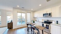 Located at 66 S Van Gordon St in Lakewood, Colorado, this one-bedroom, one-bathroom residence offers a thoughtfully designed single-level layout with modern finishes throughout. The open-concept kitchen and living area serves as the heart of the home, featuring white shaker-style cabinetry, a classic subway tile backsplash, stainless steel appliances including a range, microwave, and refrigerator, and a built-in dining bar with seating. Light wood-style flooring extends throughout the entire space, creating a cohesive and contemporary feel. A sliding glass door in the kitchen/living area leads directly to a private outdoor balcony, flooding the interior with natural light and providing outdoor views of the surrounding Lakewood neighborhood. The living room includes large windows with blinds, further enhancing the bright and airy ambiance. The bedroom is a comfortable retreat with a ceiling fan, neutral walls, and direct access to a generously sized walk-in closet outfitted with a full-length hanging rod and upper shelving. The bathroom features a full soaking tub and shower combination with floor-to-ceiling white subway tile, a sliding glass door, and wood-style flooring. An in-unit stacked washer and dryer adds everyday convenience to this well-appointed residence.