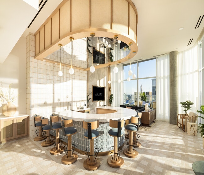 Luxurious modern kitchen with a unique curved island, elegant bar stools, and expansive floor-to-ceiling windows offering stunning city views. - Ancora
