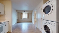 Located at 411 West Maple Street in Wichita, Kansas, this single-floor unit offers a practical and well-appointed layout designed for comfortable everyday living. Light wood-style flooring runs consistently throughout the space, lending a clean, cohesive look to every room.

The kitchen is efficiently designed with white cabinetry providing ample upper and lower storage, light countertops, and a full suite of white appliances including a refrigerator, electric range, built-in microwave, and dishwasher. Recessed lighting brightens the workspace, making it a functional area for meal preparation.

The living area is open and airy, with neutral walls and natural light flowing in through a window dressed with beige curtains. A stacked washer and dryer unit is conveniently integrated into this space, offering in-unit laundry without occupying a separate room. A second window in an adjacent area further enhances the natural light.

The bedroom is a quiet, well-proportioned room featuring the same wood-style flooring and soft neutral tones, providing a versatile and move-in-ready space. The bathroom includes a full soaking tub and shower combination, with clean white finishes and a smooth-lever door handle adding a simple, modern touch.

Overall, this unit presents a clean, functional, and well-maintained environment with consistent finishes throughout.