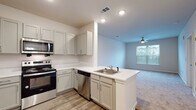 Located at 4225 East West Connector in Smyrna, Georgia, this single-floor residence offers a clean, modern aesthetic throughout. The open-concept kitchen flows seamlessly into the living area, creating a connected and functional layout. The kitchen is outfitted with gray shaker-style cabinetry, white countertops, and a full suite of stainless steel appliances including a refrigerator, range, over-the-range microwave, and dishwasher. A peninsula with an integrated sink adds additional prep space and serves as a natural divider between the kitchen and living area. Wood-look flooring runs throughout the kitchen and entry areas, while plush carpeting covers the living room and bedrooms. The living area is bright and inviting, featuring a ceiling fan and a window that overlooks an outdoor balcony. The bedrooms are comfortably sized, each with carpet flooring, neutral tones, and windows that allow ample natural light. The bathroom is finished with a gray vanity, white countertop, subway tile shower surround, and wood-look flooring, maintaining the consistent, contemporary style found throughout the home. Recessed lighting and ceiling fans contribute to a comfortable and well-lit living environment overall.